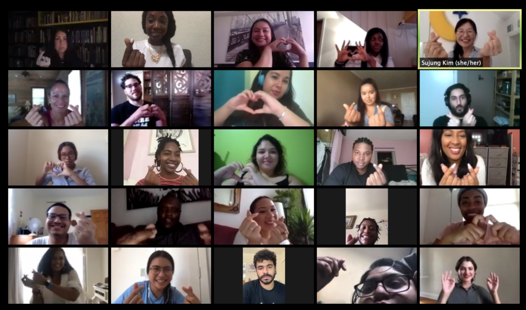 Zoom screen full of smiling faces making heart symbols with their hands